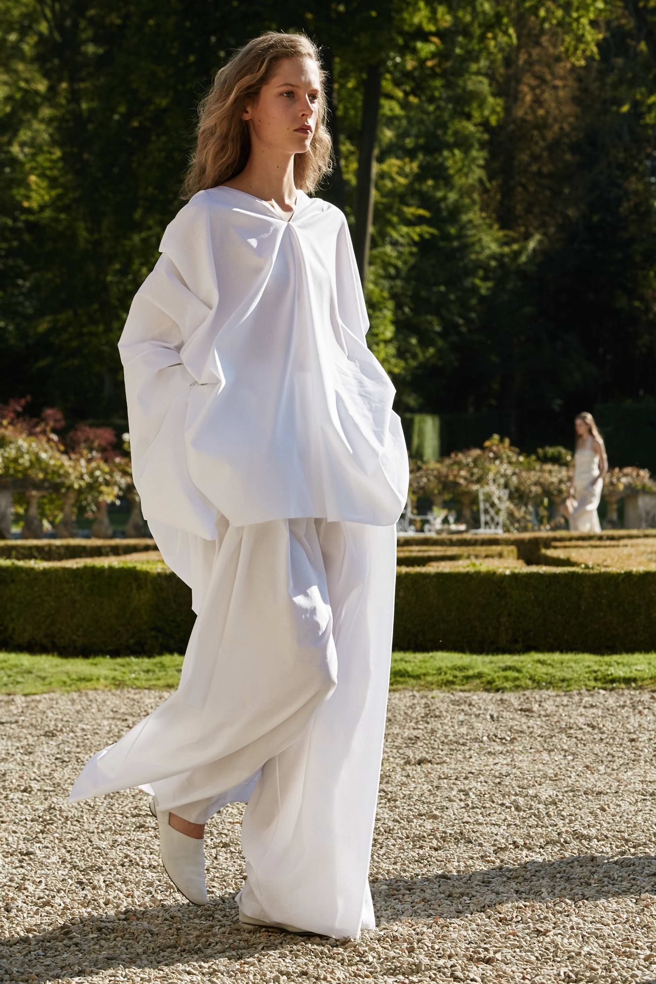 This image may contain Clothing Apparel Human Person Fashion Robe Long Sleeve Sleeve Plant Grass and Evening Dress